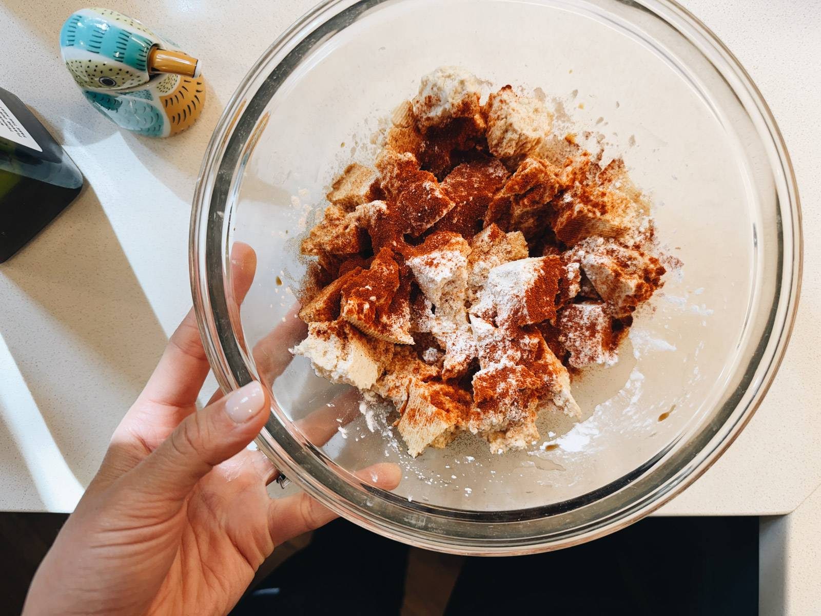 Tossing tofu in a bowl with spices and cornstarch.
