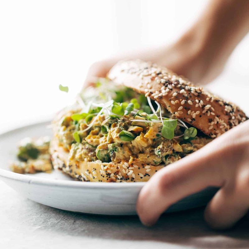 A person placing down a plate with a sandwich on it.