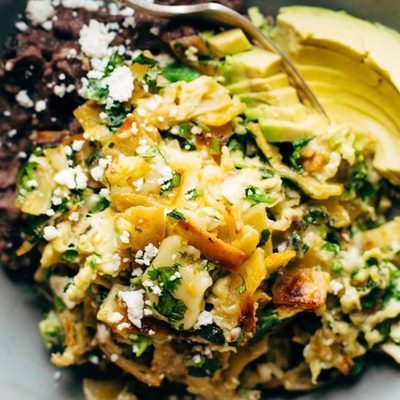 Migas in a bowl with avocado and refried black beans.