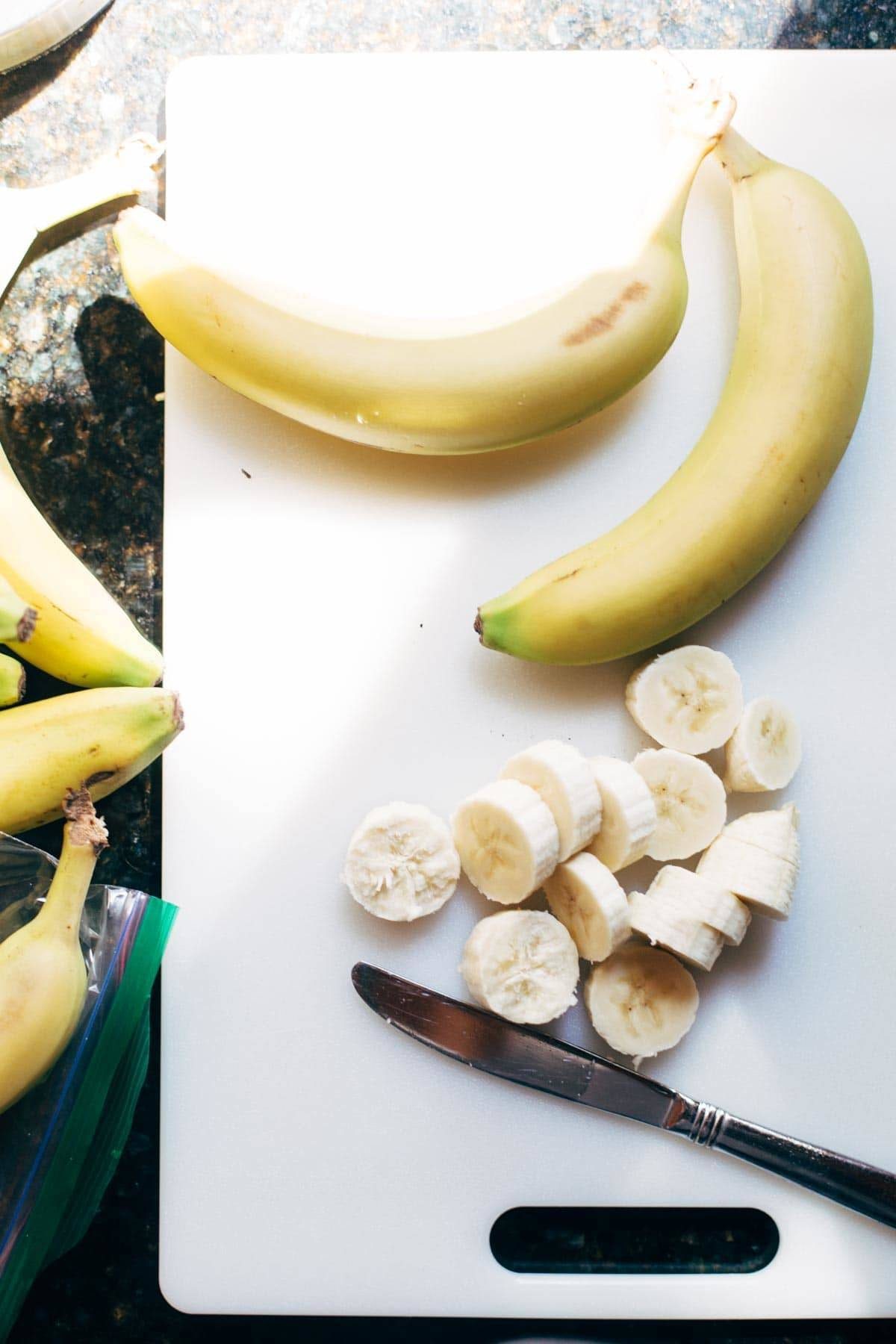 Knife with bananas on a cutting board.